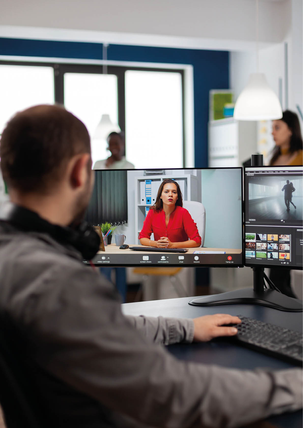 Video editor talking with remote customer in web online meeting using video call editing project, getting feedback on commercial movie using post production program on two displays in creative agency