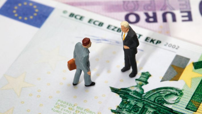 Muñequitos de un abogado y un cliente encima de billete de euro