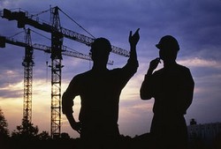 Dos obreros y un par de grúas al fondo