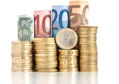 4 montones de monedas apiladas y sobre cada una de ellas un billete enrollado