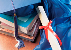 Un birrete encima de unos libros y un diploma