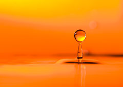 Impacto de una gota en el agua con fondo naranja.