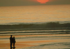Una pareja paseando por la playa en el atardecer.