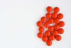 Unas pastillas rojas sobre una mesa blanca.