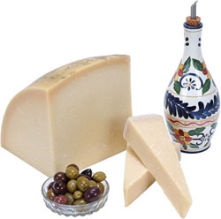 Aceitera junto a un poco de queso y un plato de aceitunas.