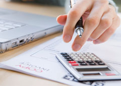 Una persona haciendo cálculos en la calculadora y el ordenador