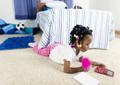 Una niña echada en el suelo jugando con la nintendo.